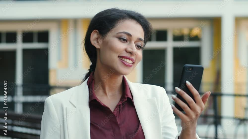 Smiling mixed race woman video chatting outside. Lady looking phone screen Smiling mixed race woman video chatting outside. Lady looking phone screen