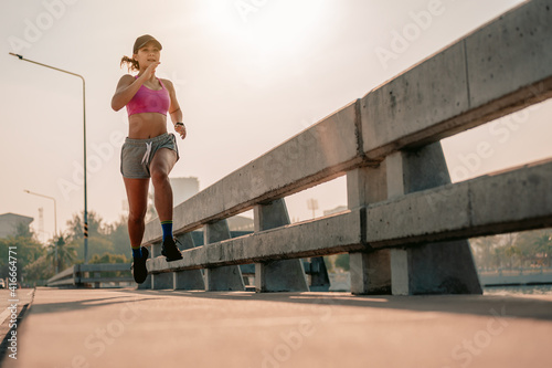 Asian women is jogging in the morning.City running Healthy living in the capital.City bridge road. Exercise, fitness, jogging, running, lifestyle, healthy concept.