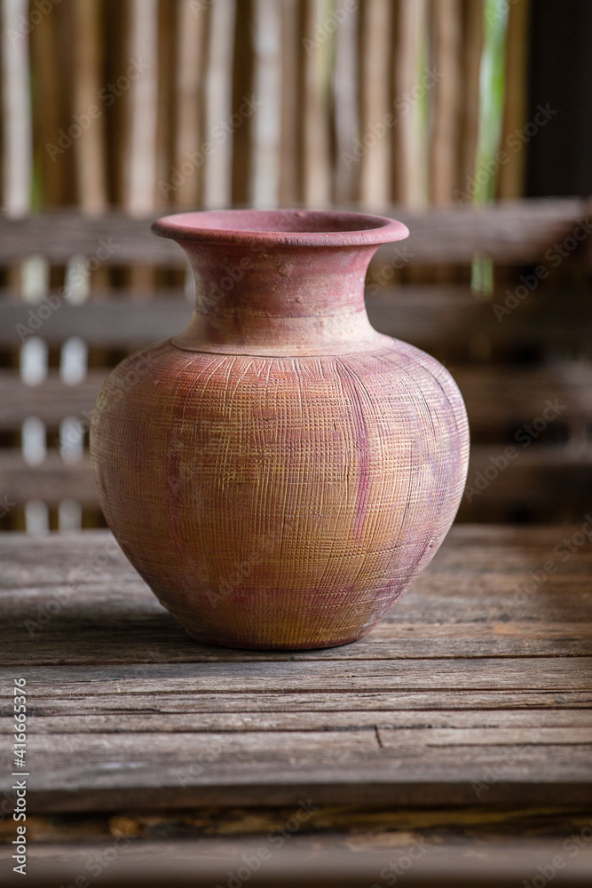 Old clay vase of manual work on wooden table in thai home Old clay vase of manual work on wooden table in thai home