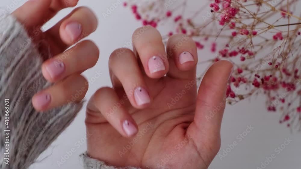 Woman showing hands with beautiful nude manicure holding delicate pink