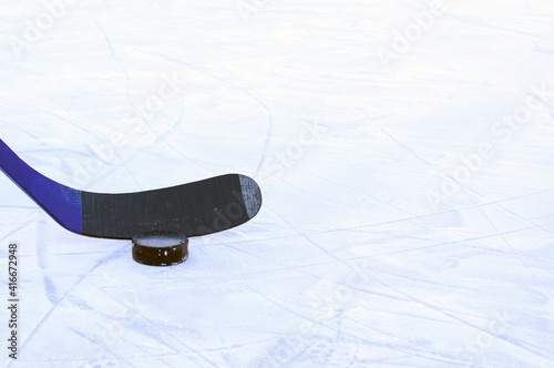 Hockey stick and puck on the rink. Copy space. Selective focus. Blurred background.