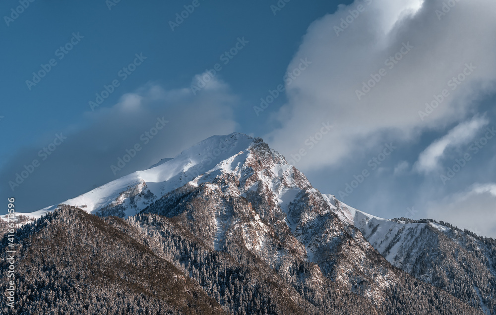 Caucasus mountains. Mount Krasnaya on Arkhyz. Snow peak and mountainside. Trees in the snow.