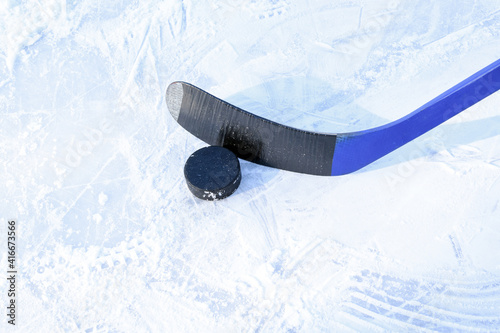 Hockey stick and puck on the rink. Copy space. Selective focus. Blurred background.