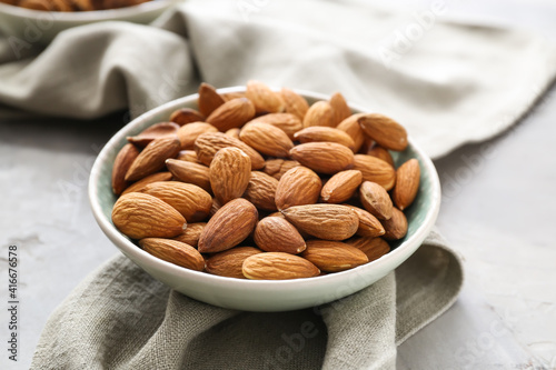 Plate with tasty almonds on grey background photo