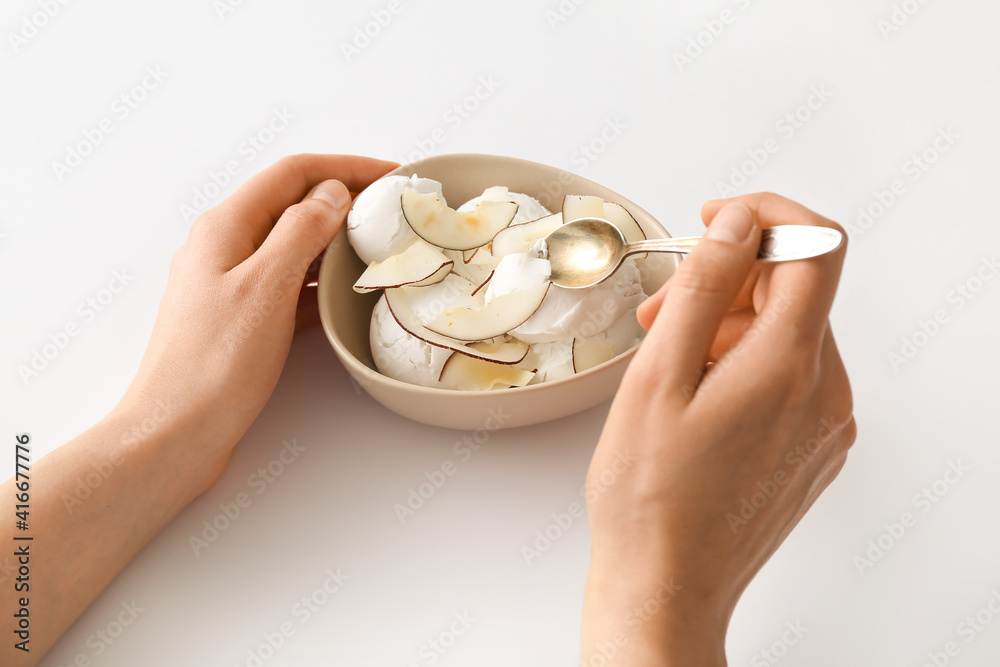 Woman eating tasty coconut ice cream on white background Woman eating tasty coconut ice cream on white background