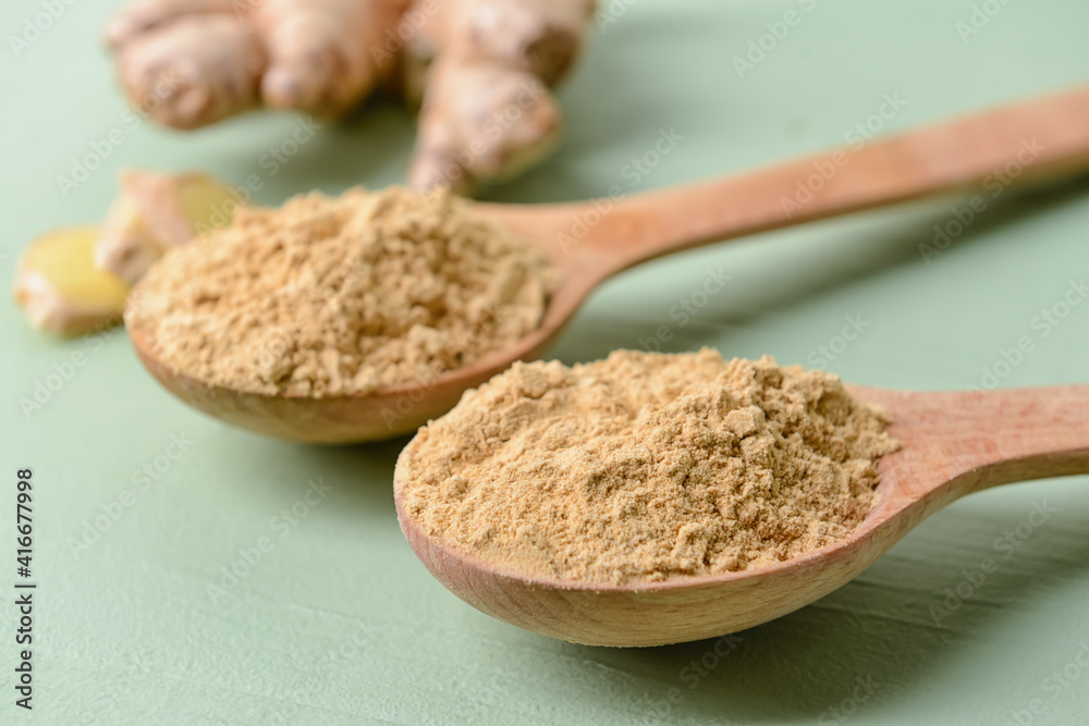 Spoons with ginger powder on color background, closeup Spoons with ginger powder on color background, closeup