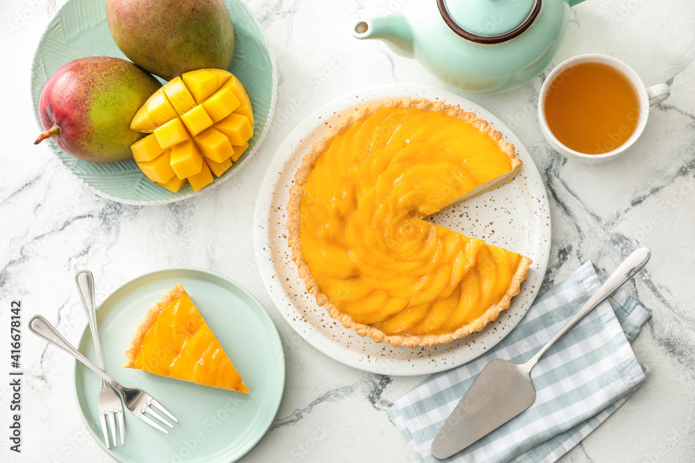 Plate with tasty mango pie and cup of tea on light background Plate with tasty mango pie and cup of tea on light background
