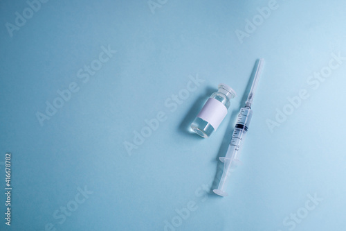 Vials with coronavirus vaccine and syringe on light background, flat lay. Space for text