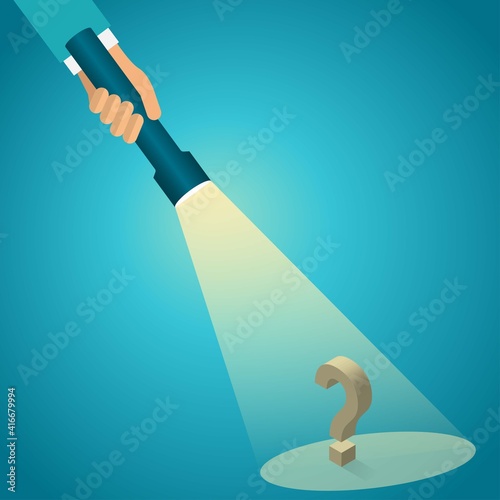 Hand of a man shines with flashlight on a question mark
