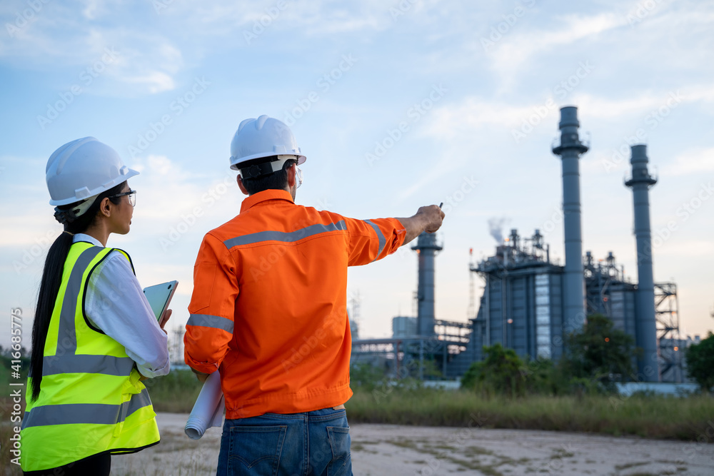 Two engineers working with laptop at front oil and gas refinery plant industry factory. Two engineers working with laptop at front oil and gas refinery plant industry factory.