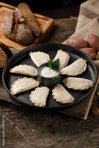 Appetizing traditional Russian dumplings, hand-made with potatoes. Still life on a wooden board. Close-up. photo