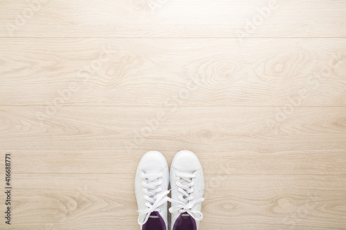 White female sport shoes for walking, running or fitness on light wooden floor background. Closeup. Empty place for motivational, inspirational text. Top down view.