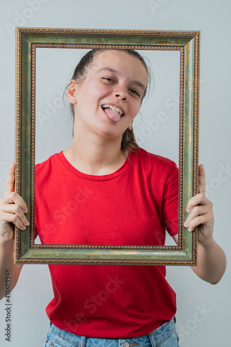 Young girl in red shirt holding a metallic photo frame