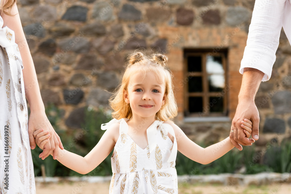Beautiful cute girl holding hands with her parents