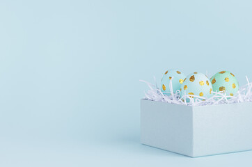 Bright and laconic easter background with blue eggs with golden dots in gift box on blue backdrop, closeup.
