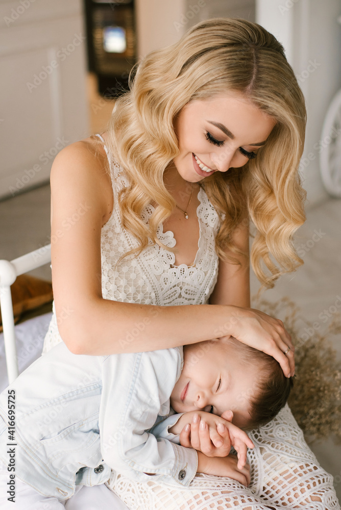 Beautiful young mother and son cuddle and play in smart clothes at home Beautiful young mother and son cuddle and play in smart clothes at home