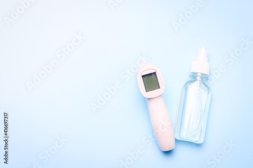 infrared thermometer and antiseptic on a blue background . antiseptic. treatment of hands. prevention. non-contact temperature measurement. health. coronavirus. pandemic. human health. check the tempe