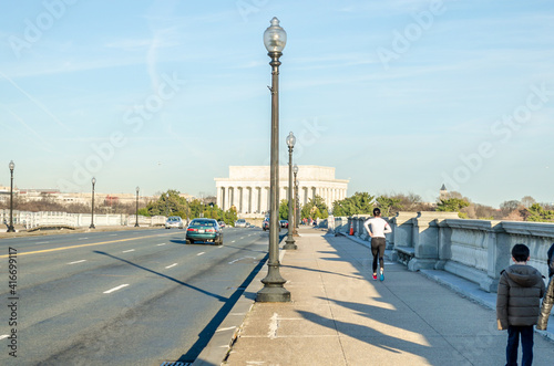 Arlington Bridge Leads to Lincoln Memorial in Washington DC, USA. Vehicles Crossing the Bridge and People Walking and Hiking on the Pavement on a Sunny Day.