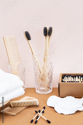 Eco friendly lifestyle concept. Zero waste products for the home. Contemporary still life with biodegradable bamboo toothbrushes, bamboo ear sticks, wooden combs and reusable cotton sponges photo