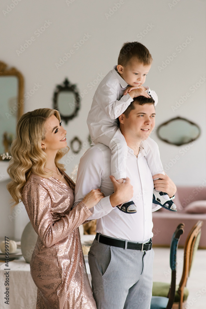 Fototapeta premium Beautiful young family man woman and son in smart clothes in a luxurious bright interior, happy family