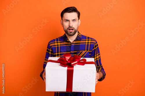 Photo of shocked unsatisfied person hands hold giftbox open mouth staring isolated on orange color background © deagreez