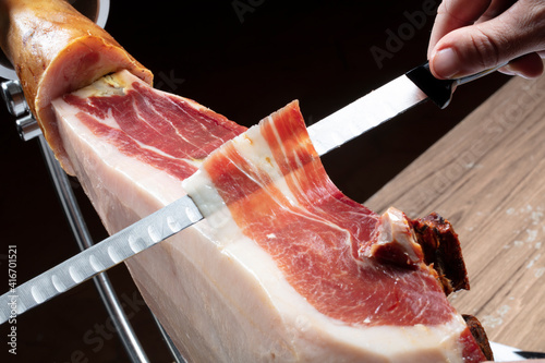 jamón serrano ibérico, mano cortando jamón con cuchillo. Iberian serrano ham, hand cutting ham with knife.