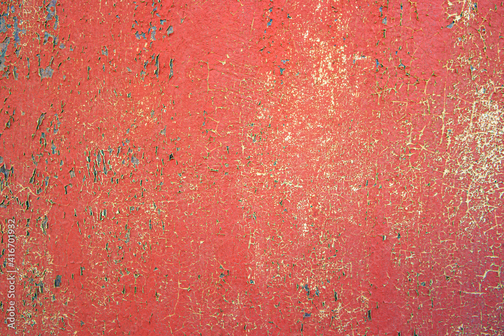Peeling and cracked red paint on the wall surface