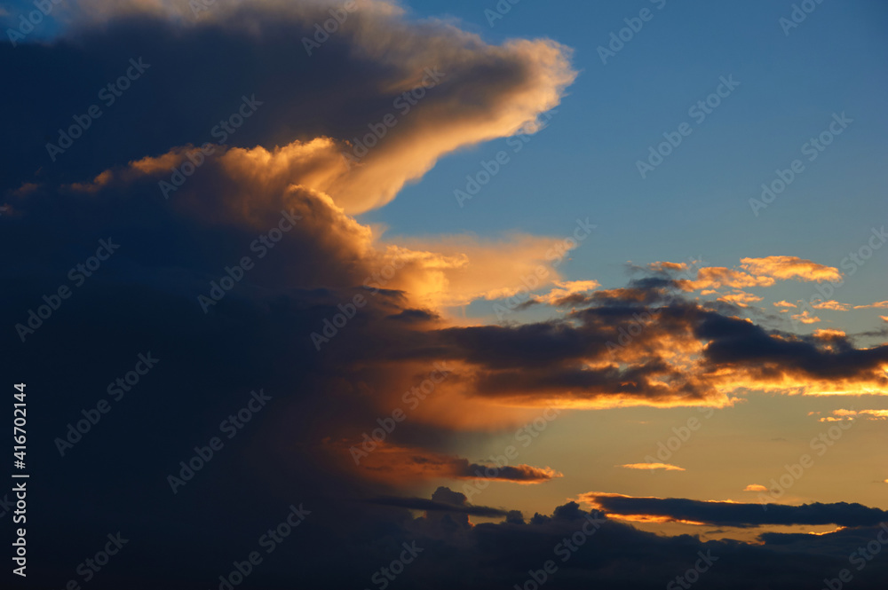 Monumental clouds against the sky are illuminated by the setting sun. Cumulus clouds at sunset. Monumental clouds against the sky are illuminated by the setting sun. Cumulus clouds at sunset.