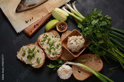 Traditional Jewish snack vorschmack or forshmak with bread and green onion, made of herring fillet and served with rye bread, dark stone background photo