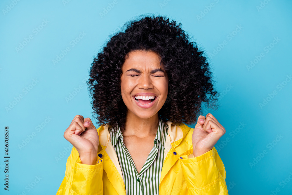 Portrait of delighted dark skin person closed eyes fists up celebrate unexpected luck isolated on blue color background Portrait of delighted dark skin person closed eyes fists up celebrate unexpected luck isolated on blue color background