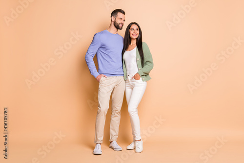 Full size photo of optimistic nice couple stand look empty space wear sweater isolated on beige color background