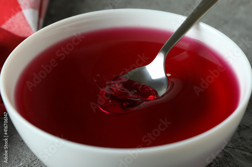 Bowl of red jelly on gray textured table, close up