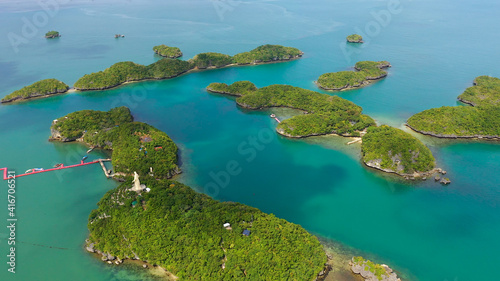 Fototapeta Naklejka Na Ścianę i Meble -  Islands in blue water covered with vegetation with beaches and bays where tourists rest. Hundred Islands National Park, Pangasinan, Philippines. Alaminos. Summer and travel vacation concept