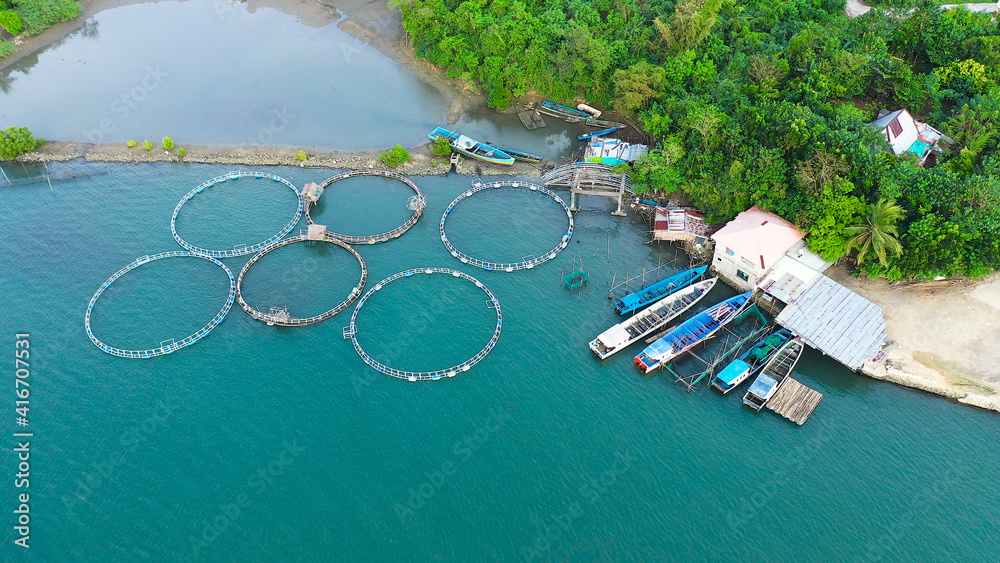 Fish farm with cages for fish and shrimp, top view. Fish cage for tilapia,  milkfish farming aquaculture and pisciculture practices. Philippines,  Luzon. Aerial view of fish ponds for bangus, milkfish. Stock Photo