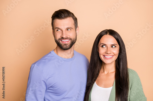 Photo of young happy smiling cheerful lovely couple husband and wife look copyspace isolated on beige color background