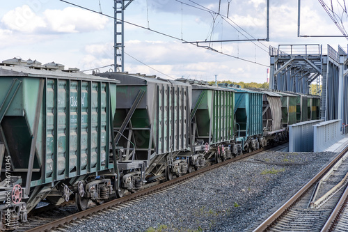 Freight train with covered hoppers passes the bridge. Hopper - self-clearing enclosed railroad freight car for dry and bulk loads. Rail freight