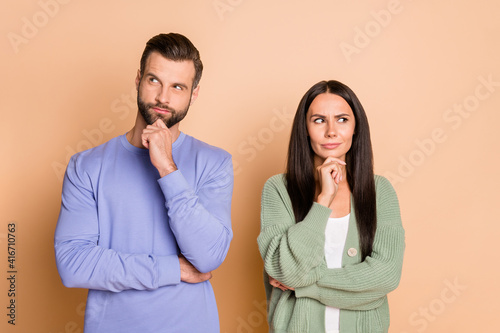 Portrait of optimistic couple fist chin look empty space wear cardigan sweater isolated on beige color background