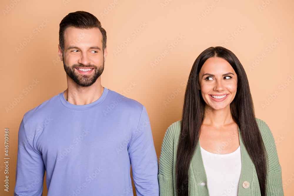 Portrait of optimistic couple look each other wear cardigan sweater isolated on beige color background