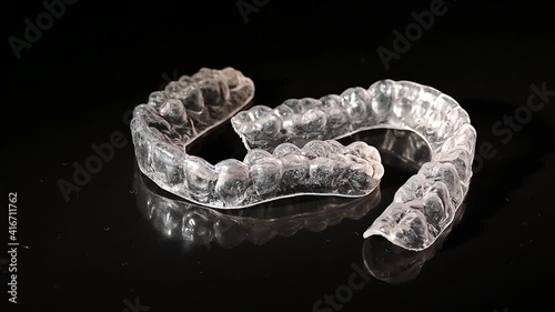 Transparent removable braces swirls around on a black background