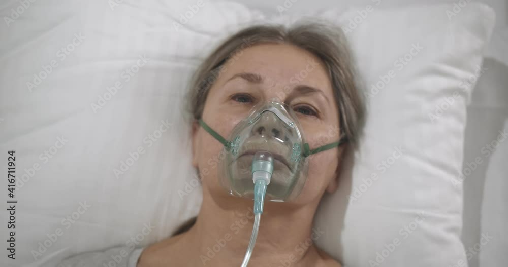 Close-up of covid-19 patient with oxygen mask in bed in hospital