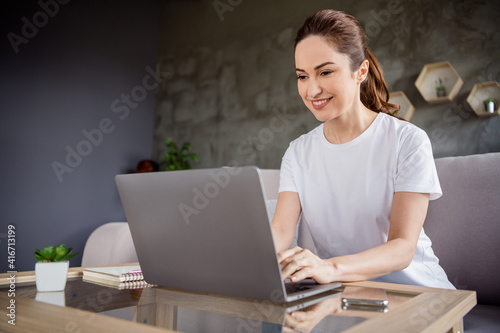 Portrait of attractive cheerful lady beaming smile use laptop typing email working from home indoors