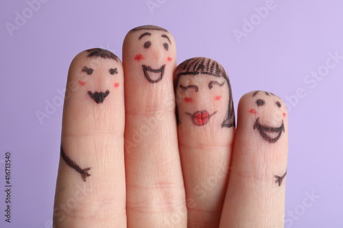 Four fingers with drawings of happy faces on violet background