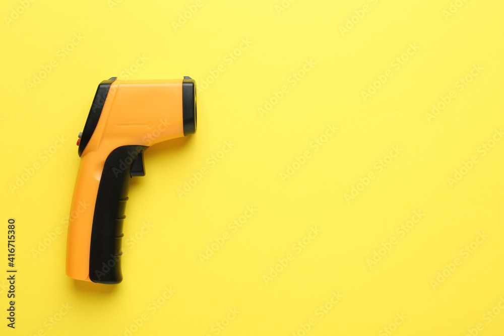Infrared thermometer on yellow background, top view with space for text. Checking temperature during Covid-19 pandemic Infrared thermometer on yellow background, top view with space for text. Checking temperature during Covid-19 pandemic