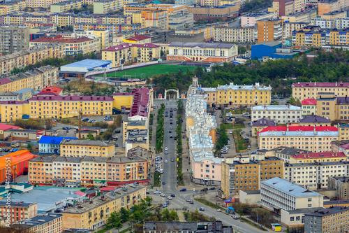 Aerial view of the city of Magadan. Portovaya street and the arch with the text in Russian "City Park". Cityscape with streets, buildings and stadium. Magadan, Magadan Region, Far East Russia. Siberia
