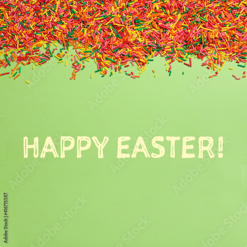 Text Happy Easter and colorful sprinkles on green background, flat lay. Confectionery decor