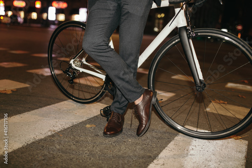 Elegant businessman with bicycle standing on crosswalk
