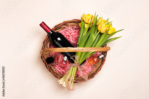 Bottle of red wine  tulip flowers and cosmetic in gift basket for Women s day and month  Mother s Day  birthday