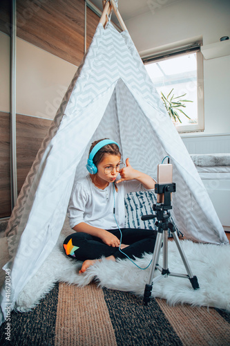 Little girl using a cellphone in her room in a tent.