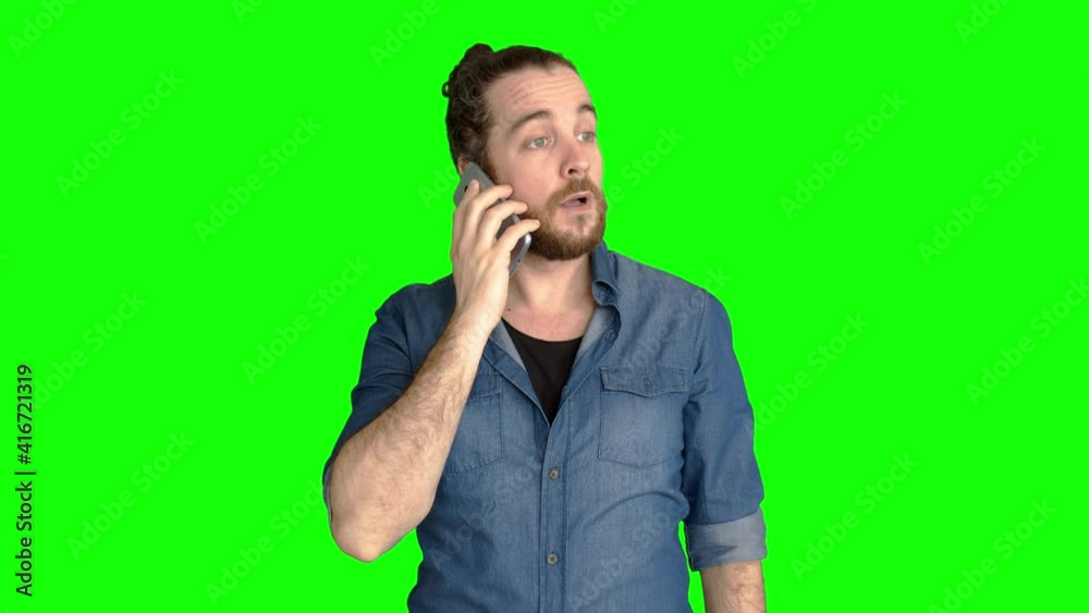 Young man wearing a casual blue shirt gets a phone call.
Italian man with long hair, beard and hair bun gets an happy phone call. Green screen.