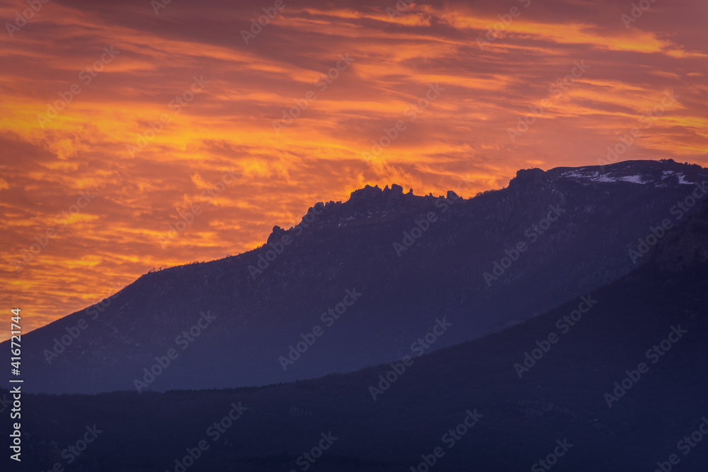 Sunset pink, red glow over the mountains. Atmospheric majestic sky landscape. A combination of orange and purple. Natural background at dusk, mountain tops, without people. The concept of tranquility